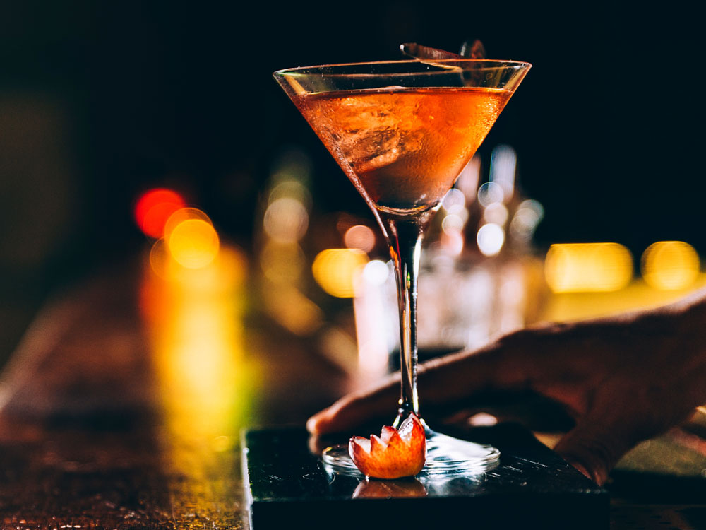 Martini on a dark bar with moody yellow lights in background